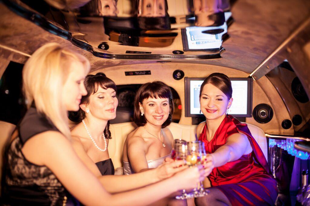 Group of friends celebrating something in luxury limousine and drinking champagne. Luxury lifestyle.